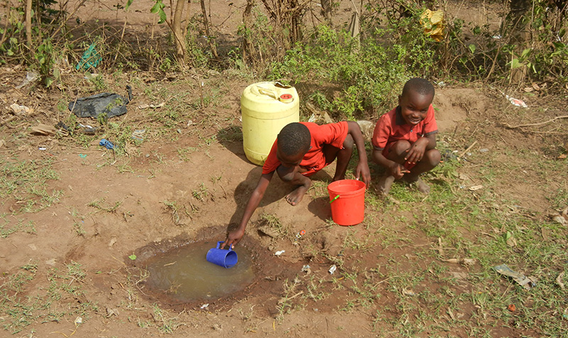 Enfants récupérant l'eau dans une flaque