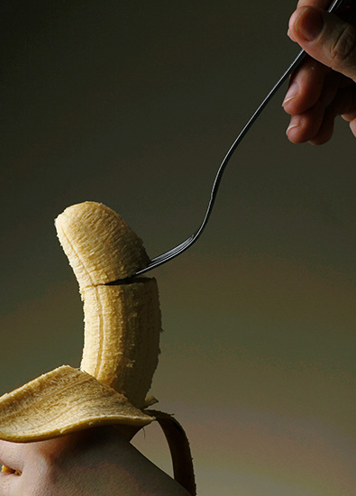 Une main avec un cuillère coupe la banane Une main avec un cuillère coupe la banane