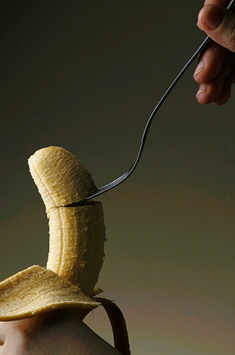 Une banane est découpée par une main avec une cuillère