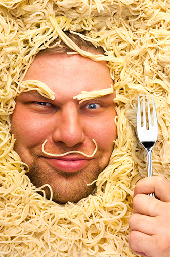 Un homme entouré de spaghetti et une fourchette à la main