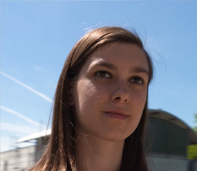 Une femme qui marche devant des bâtiment, gros plan sur la tête