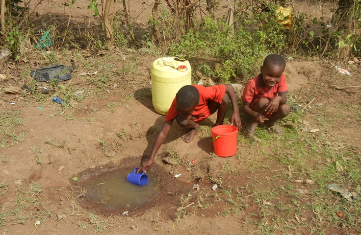 Enfants récupérant l'eau dans une flaque